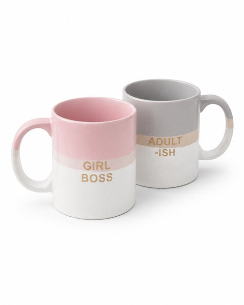 Two ceramic mugs on a white background, one pink and white with gold text reading 'GIRL BOSS' and one gray and white with gold text reading 'ADULT -ISH'.