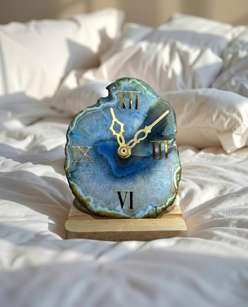 Decorative clock with blue agate design on a wooden base, placed on a bed.