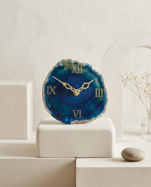 Decorative clock with blue agate-like face on a white surface