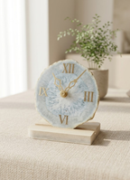 Decorative clock with Roman numerals on a wooden base in a home setting