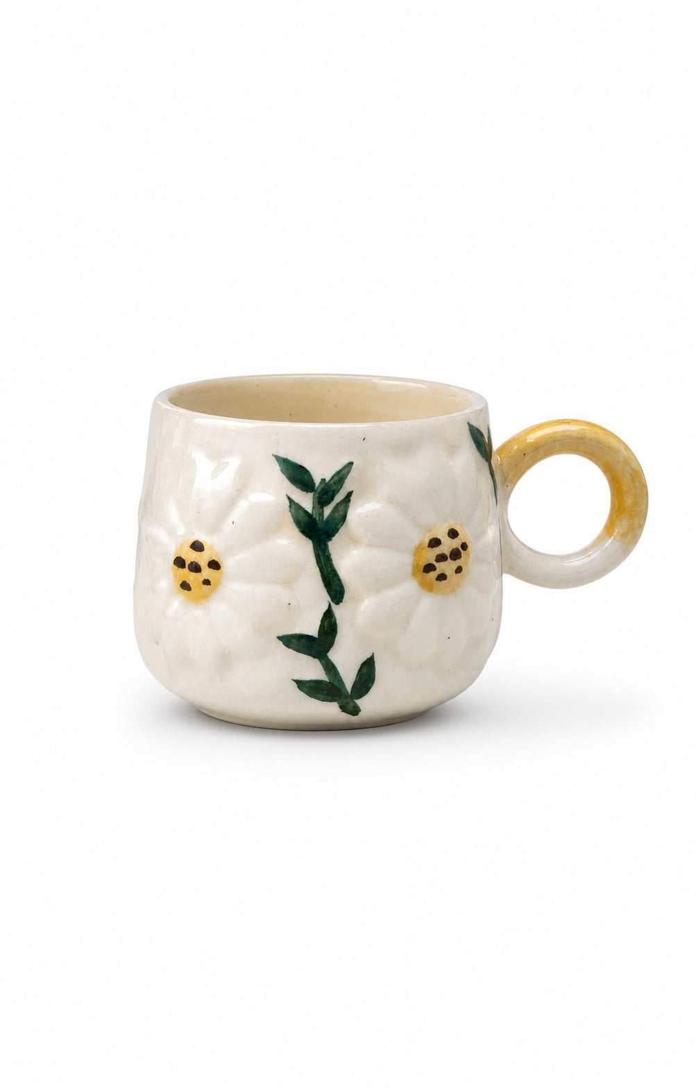 A small white ceramic mug with a textured surface, decorated with green leaves and yellow flowers, featuring a gold-toned handle and interior.
