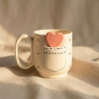 Ceramic mug with a heart-shaped cookie on a beige background