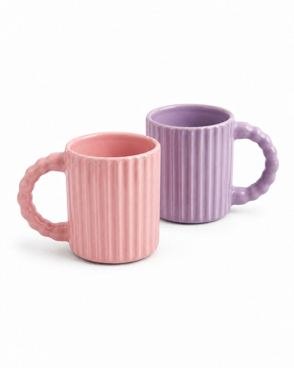 Two ribbed ceramic mugs with textured handles, one in soft pink and one in light purple, shown on a clean white background.