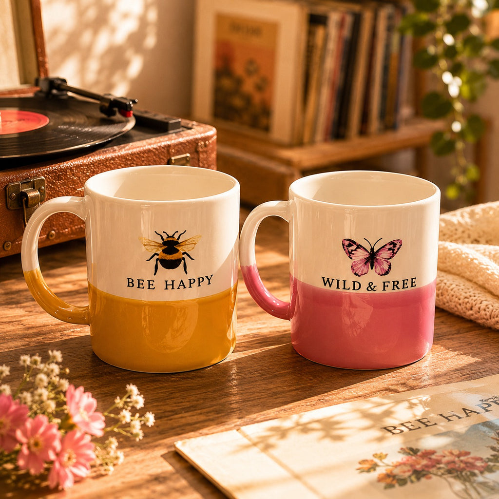 Two mugs with animal-themed designs and text on a wooden surface.
