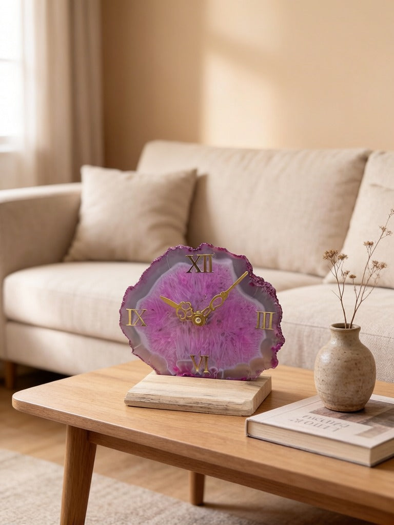 Pink agate clock on a wooden table with a beige sofa and decorative items in the background