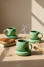 Three green ceramic mugs on a wooden surface with steam rising from one of them.