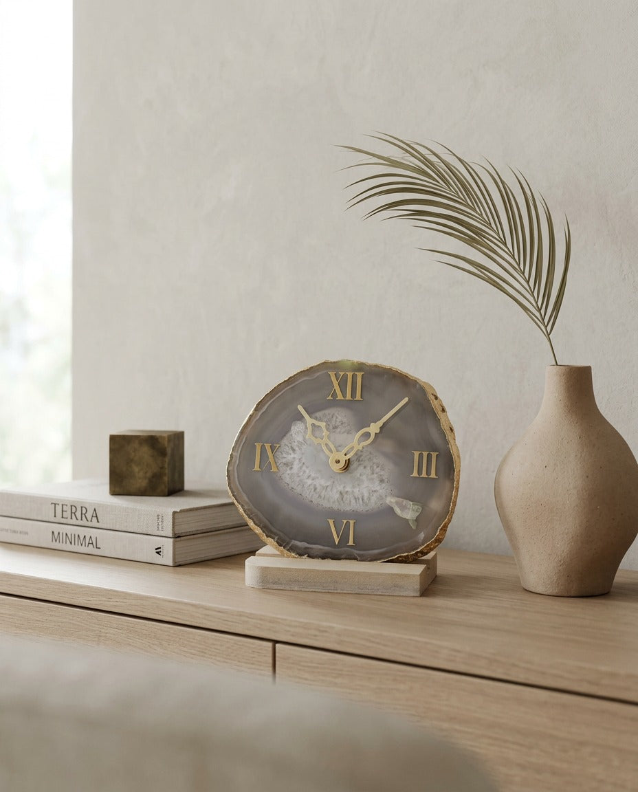 Decorative clock on a wooden surface with books and a vase in the background