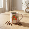 Coffee mug with orange design on a wooden table with coffee beans and steam.