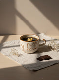 Cup of coffee with a bear cookie in it on a light surface with decorative elements.