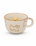 An off-white ceramic teacup with brown line-art dog illustrations and a small yellow dog figurine peeking out from inside the cup, set against a plain white background.