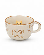 An off-white ceramic teacup with brown line-art dog illustrations and a small yellow dog figurine peeking out from inside the cup, set against a plain white background.