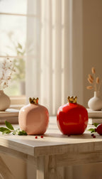 Two decorative pomegranate-shaped vases on a wooden table with a blurred background