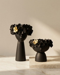 Two black vases with floral designs on a neutral background