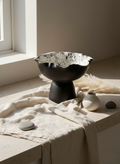Decorative black bowl with a textured surface on a light-colored surface with a neutral background