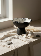 Decorative black bowl with a textured surface on a light-colored surface with a neutral background