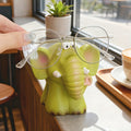 Green elephant-shaped glasses holder with glasses on a table.