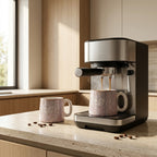 Espresso machine pouring coffee into a speckled mug on a wooden countertop.