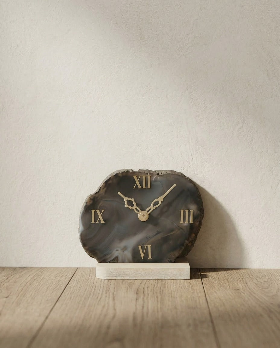 Decorative clock with Roman numeral design on a wooden surface and light background