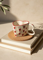 Heart-patterned mug on a stack of books with a cork coaster