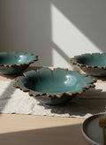 Three ceramic bowls with scalloped edges on a wooden table with a soft light background