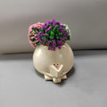 Ceramic planter with cartoon face and flowers on a neutral background