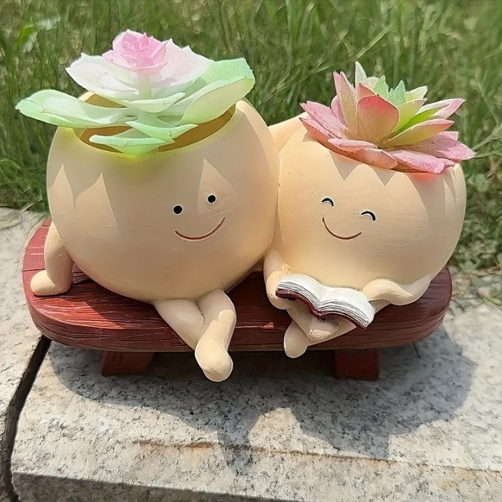 Two smiling ceramic plants with flowers on a stone surface