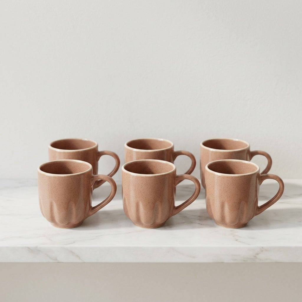 Set of six terracotta mugs on a light surface with a neutral background