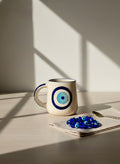 Ceramic mug with blue design on a table with a napkin and decorative items.