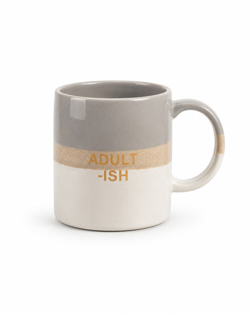 A ceramic coffee mug with a horizontal color-blocked design featuring a gray top half, a textured beige middle band with the text 'ADULT -ISH' in gold, and a white bottom half.