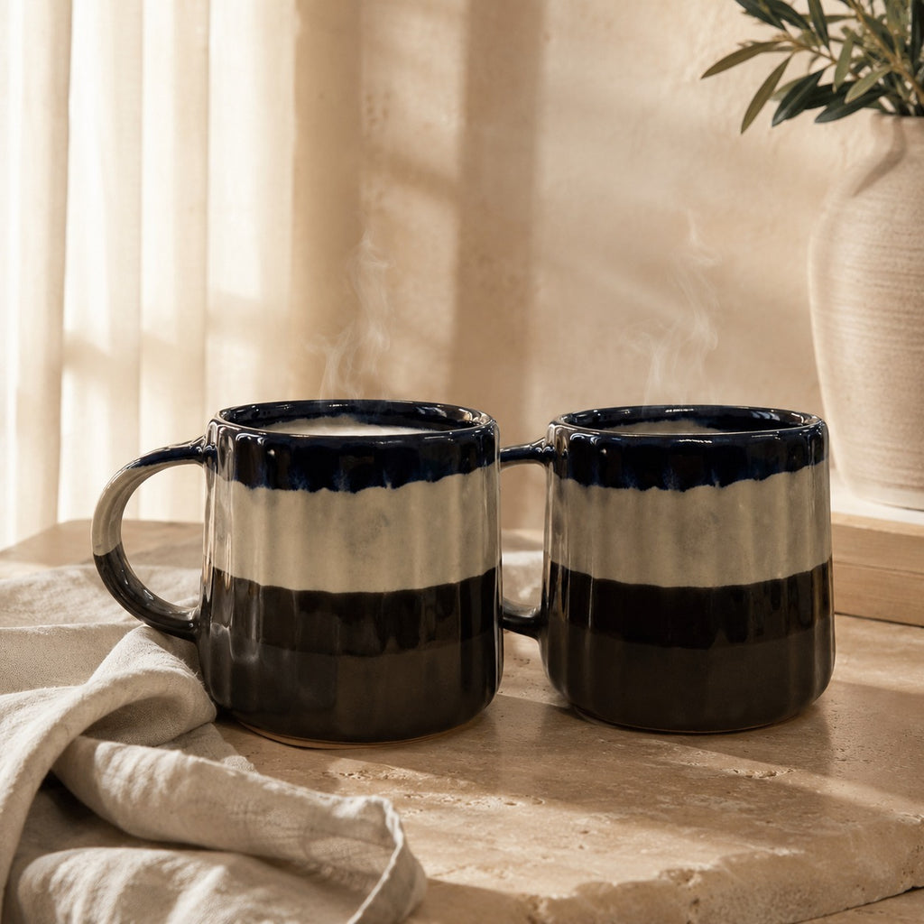 Two black and white striped mugs on a wooden surface with a neutral background