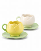 Two tulip-shaped ceramic cups with matching saucers, one in pastel yellow and one in pastel cream, set against a plain white background.