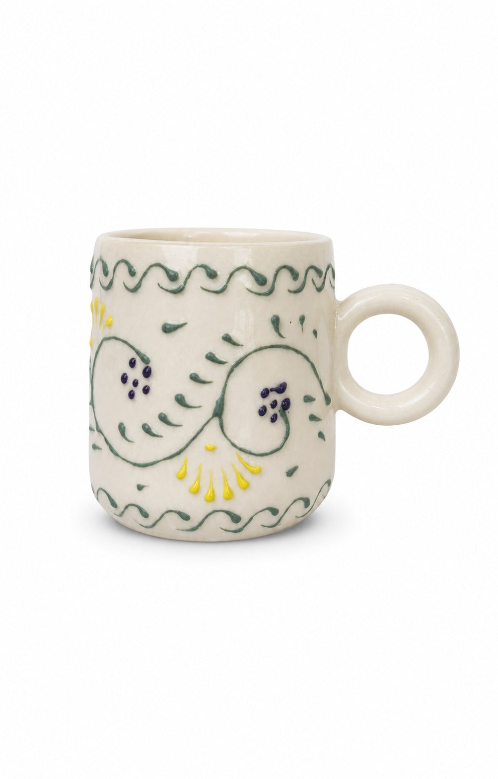 An off-white ceramic mug with a loop handle, decorated with hand-painted green and yellow floral and wavy patterns, set against a plain white background.