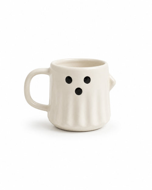 An off-white ceramic mug shaped like a ghost, featuring a simple black face with two eyes and a dot mouth, set against a plain white background.
