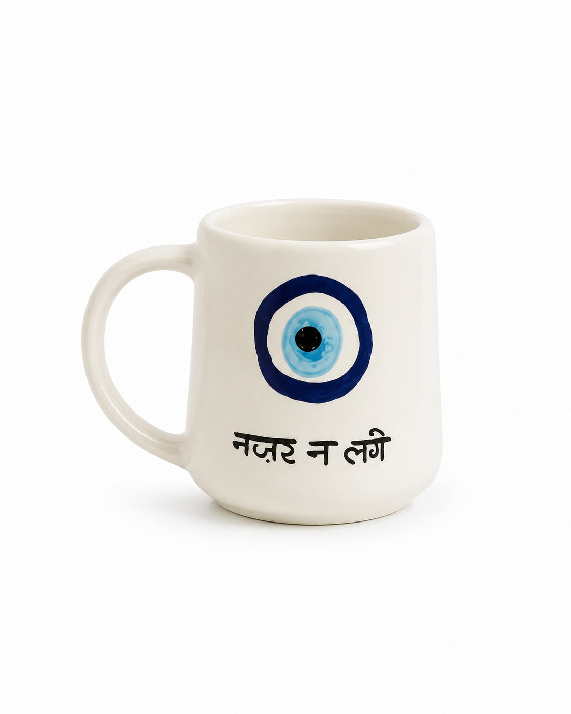 A white ceramic mug featuring a blue and black evil eye graphic and the Hindi text 'नजर न लगी' in black, set against a plain white background.