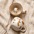 Two ceramic mugs with dog designs on a textured beige surface