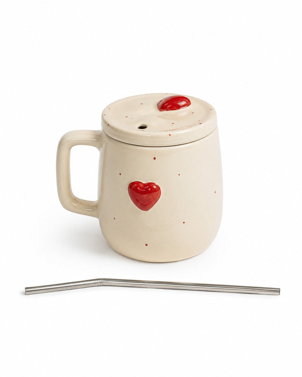An off-white ceramic mug with a matching lid, decorated with small red hearts and dots, shown with a bent stainless steel straw on a white background.