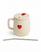 An off-white ceramic mug with a matching lid, decorated with small red hearts and dots, shown with a bent stainless steel straw on a white background.