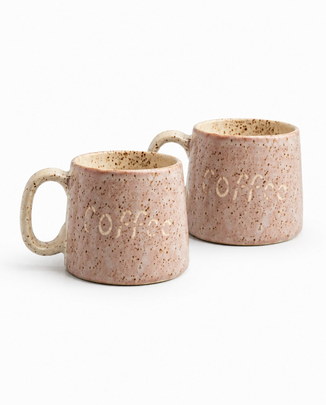 Two speckled ceramic mugs with a warm beige and pinkish-brown glaze, featuring the word 'coffee' embossed on the front, set against a plain white background.