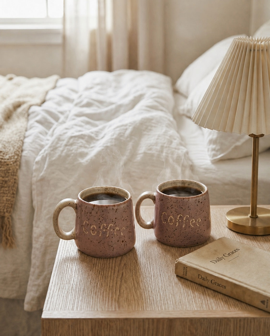 Two ceramic mugs labeled 'Coffee' on a wooden nightstand next to a lamp and book, with a bed in the background.