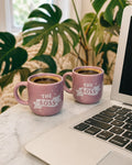 Two pink mugs labeled 'The Boss' on a laptop with a plant in the background