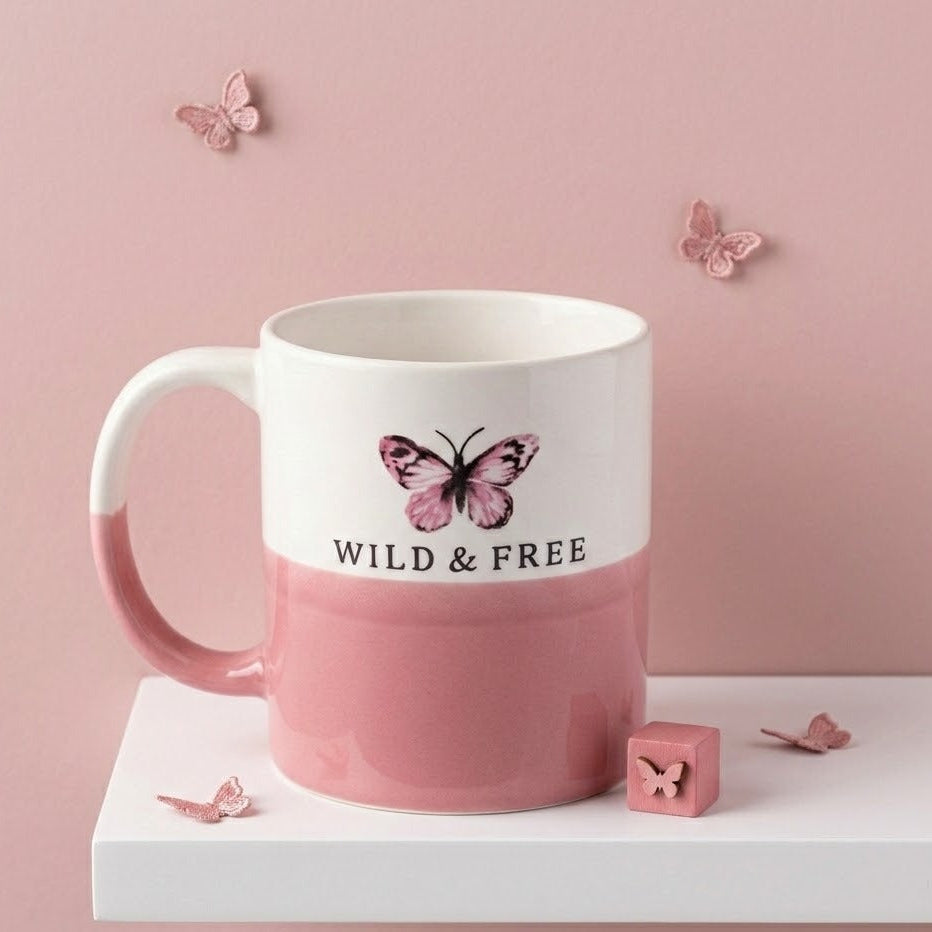 Pink mug with butterfly design and 'Wild & Free' text on a pink background